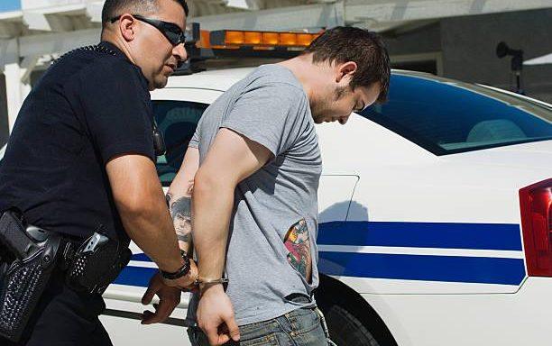 Kentucky arrest scene showing handcuffed person with law enforcement officer, representing criminal defense rights after arrest