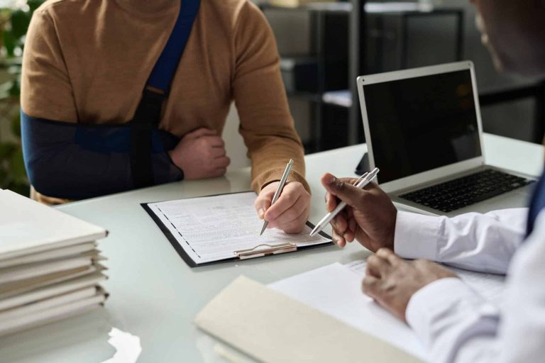 Injured worker taking notes while discussing workers compensation case with experienced attorney